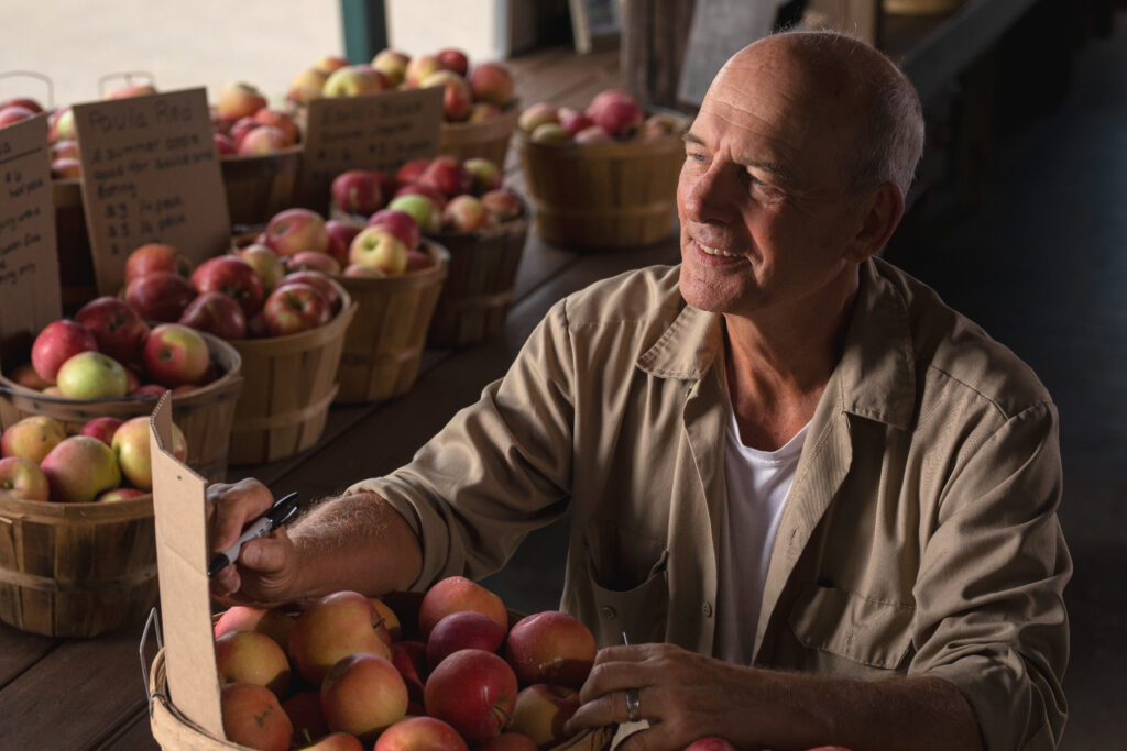 Man looking at apples in barrels