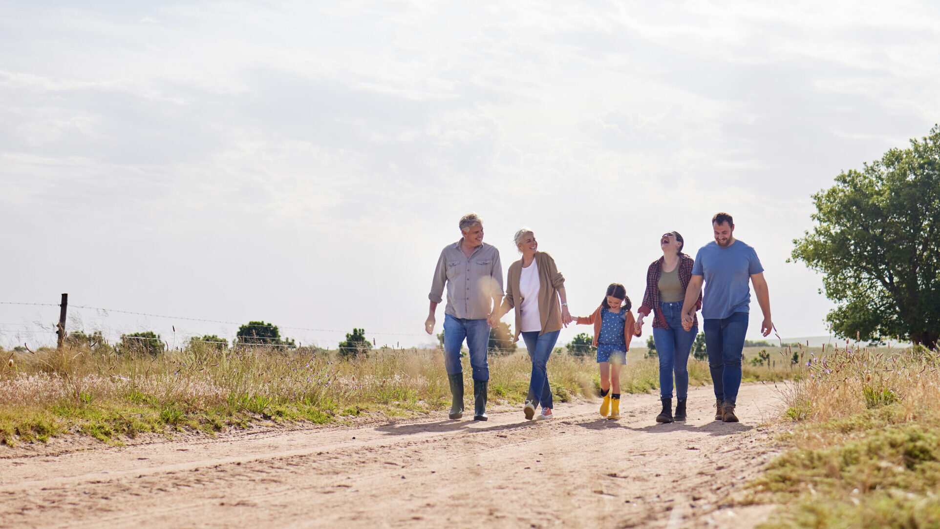 Family walking together on a dirt path through farmland.